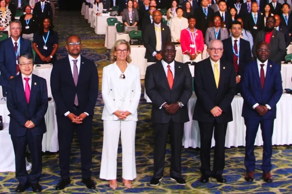 Prime Minister Davis, Minister Bastian, and ITU Executives in photo standing before the room of delegates.  Pictured from left: Seizo Onoe, Director of ITU Telecommunication Standardization Bureau; the Hon. Sebastian Bastian, Minister of Innovation & National Development; Doreen Bogdan-Martin, Secretary-General, ITU; Prime Minister the Hon. Philip Davis; Mario Maniewicz, Director of ITU Radiocommunication Bureau; and Dr. Cosmas Luckyson Zavazava, Director of ITU Telecommunication Development Bureau.